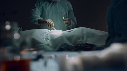 Professional surgeon making incision before operating in dark surgery room.