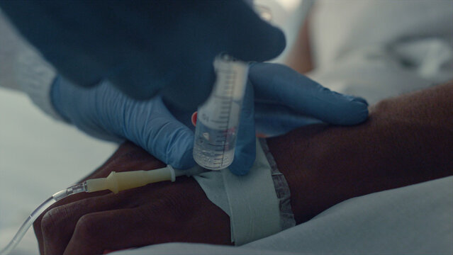 Doctor putting patient IV doing injection closeup. Hospital intensive care unit