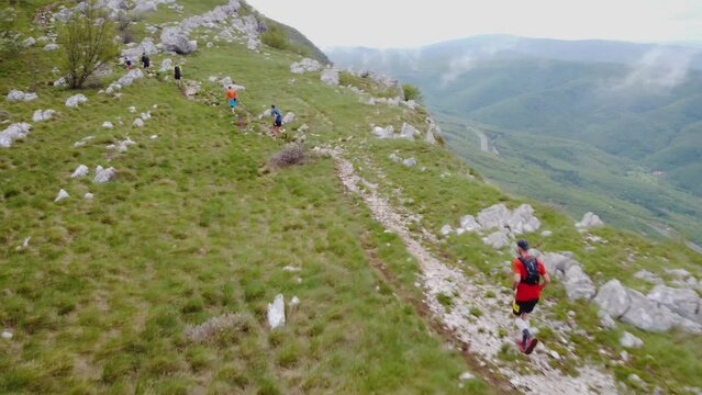 Ultra trail runners running uphill near the mountain top - 4k aerial view
