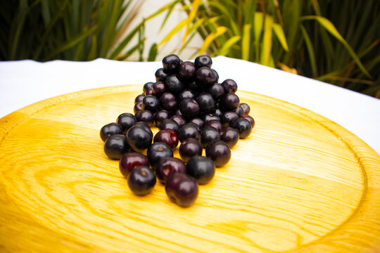 Close up of a bunch of sweets capulin cherries on a wooden board, with a background nature. Spring red berries. Capulines.