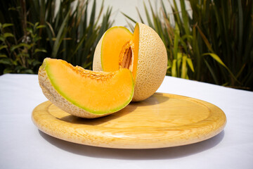 Delicious sliced ​​fruit melon, honeydew melon or cantaloupe on wooden board with nature background. Favorite fruit in summer on white background.