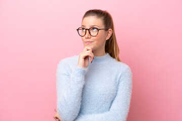 Young caucasian woman isolated on pink background and looking up