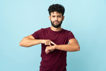 Young Moroccan man isolated on blue background making the gesture of being late