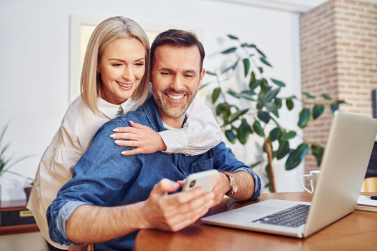 Happy middle aged couple doing online payment with mobile phone