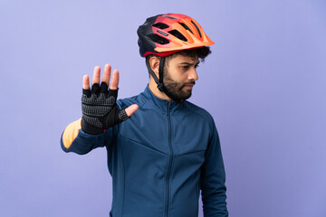 Young Moroccan cyclist man isolated on purple background making stop gesture and disappointed - obrazy, fototapety, plakaty