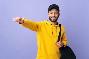 Young sport Moroccan man with sport bag isolated on purple background giving a thumbs up gesture