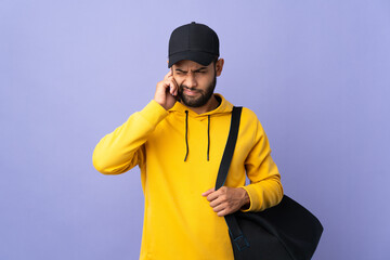 Young sport Moroccan man with sport bag isolated on purple background frustrated and covering ears