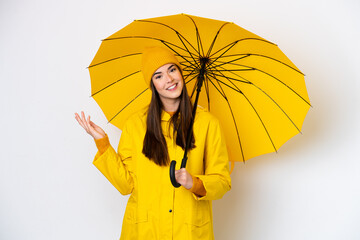 Young Brazilian woman with rainproof coat and umbrella isolated on white background extending hands...