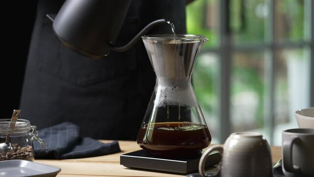 Professional barista preparing coffee using chemex pour over coffee maker and drip kettle. Alternative ways of brewing coffee. Coffee shop concept.
