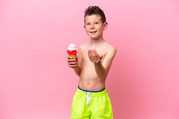 Little caucasian boy eating an ice-cream isolated on pink background inviting to come with hand. Happy that you came