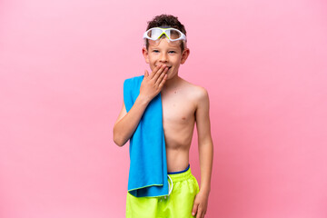 Little caucasian boy wearing a diving goggles isolated on pink background happy and smiling covering mouth with hand