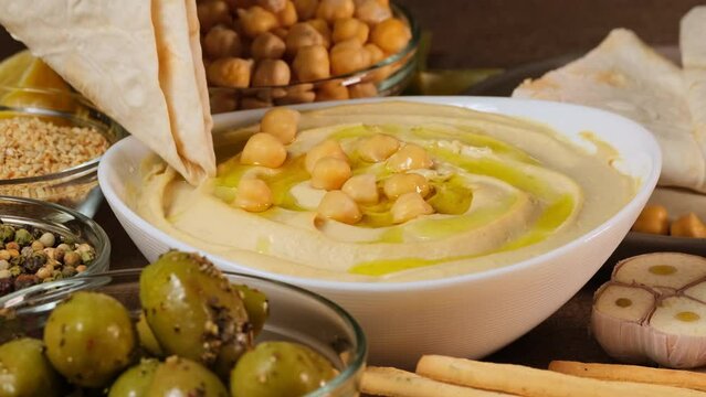 Chickpea hummus made from mashed chickpeas dip with tahini, lemon, garlic and olive oil close up. Enjoying yummy hummus with pita lavash bread. Kosher healthy vegan food. Lean vegetarian dish rotation