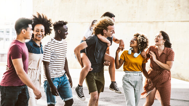 Multiracial Young People Having Fun Together Walking On City Street - Happy Group Of Friends Socializing Outside - Friendship Concept With Guys And Girls Smiling And Joking In Summer Day Out