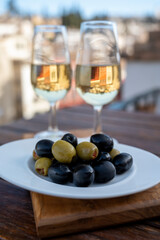 Glass bowl with black andalusian olives served with sherry wine on outdoor terrace with view on old part of Granada, Andalusia, Spain