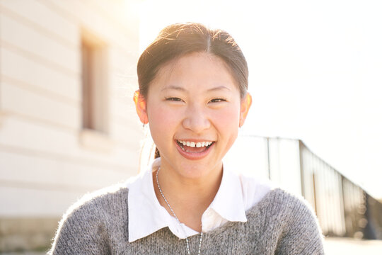 Outdoor portrait of a smiling Chinese girl looking at the camera laughing with positive face and friendly look. Close up of a Happy human face - Cheerful Asian girl. Concept of people and emotions.
