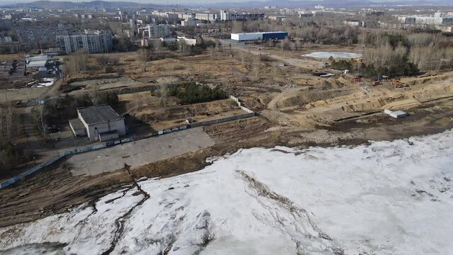 Ice on the River next to a City, Mountains Ridge cover Forest, Aerial view 