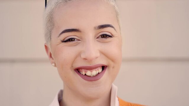 Portrait of young woman looking at camera. Close up face of cheerful girl smiling outdoor. Confident beautiful happy empowered entrepreneur shaved hair lady
