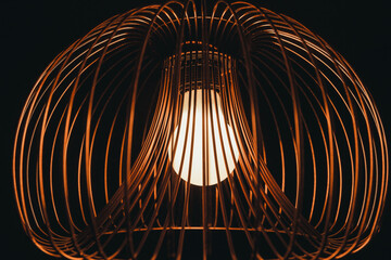 A round lamp with a rectangular iron frame suspended from the ceiling, illuminating in gold