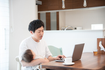 Obraz na płótnie Canvas 育児をしながら家で仕事をしている男性