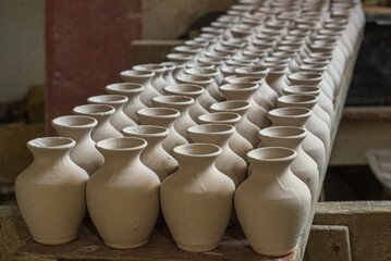 Handmade vases, cups arranged next to each other ready for firing