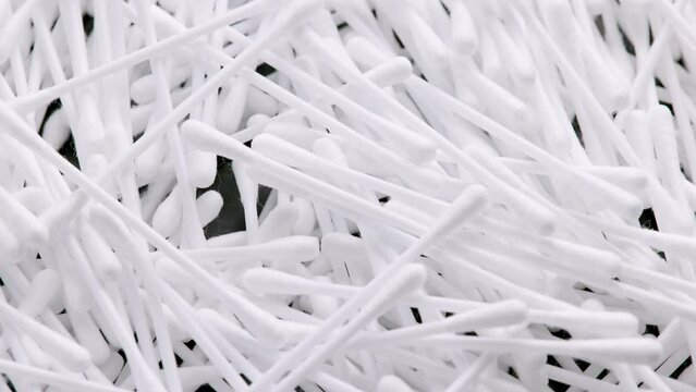 pile of q-tips or cottom buds slowly rotating on black background, loopable