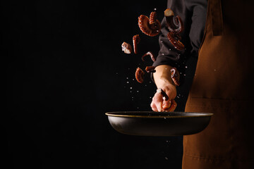 A professional chef cooks octopuses in a frying pan on a black background. Seafood in frozen...