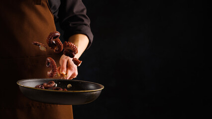 Cooking seafood by a professional chef on a black background. Seafood - octopus in a frozen flight. There is free space to insert. Healthy vegetarian food, gourmet dish.