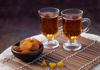Two cups of hot tea with dried apricots on wooden table in the garden. High quality photo