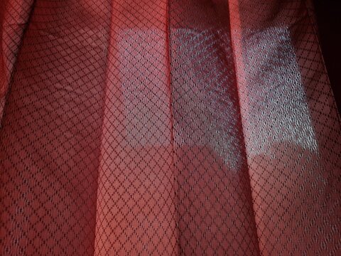 Abstract textured background of folded red window curtain fabric and combined shadows