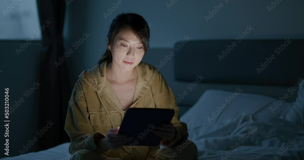 Poster Woman read on tablet computer and sit on bed at night