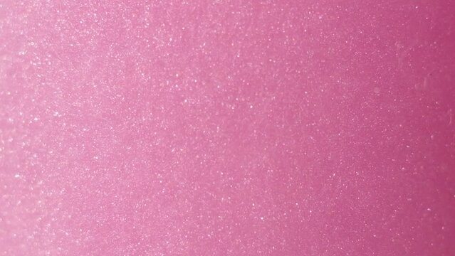 Glittering abstract pink background. Color fluid is swirling in beautiful silver clouds. Glitter dust is moving slowly in water. Amazing abstract texture background.