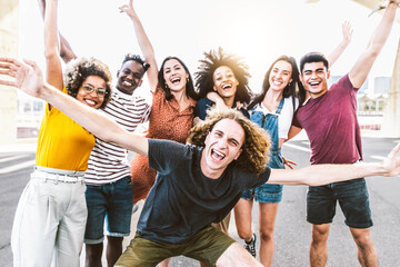 Big group of happy friends stands on city street with raised arms together - Multiracial young...