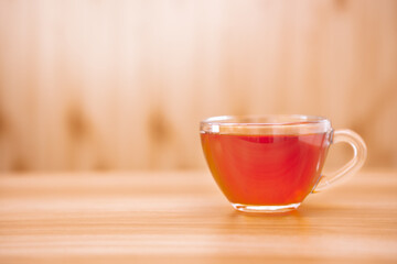 Glass cup of black tea on the wooden table with copy space