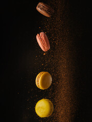 Macaroons in a flow of chocolate dust in a frozen flight on a black background. Holiday, birthday, romantic date, sweet food, calories. Advertising, banner, invitation.