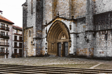 Fototapeta na wymiar Entrance door and main facade of old stone church in Guernica, Basque Country, Spain. Romanesque architecture concept.