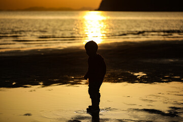 child running on the beach at sunset