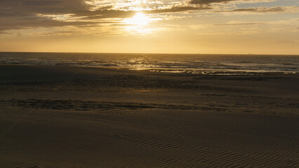 sunset during golden hour at sandy beach, De Haan, Belgium