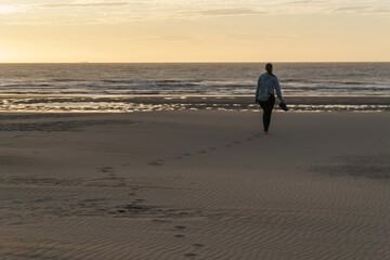 Naklejka premium footprints in the sand at the beach during golden hour at sunset
