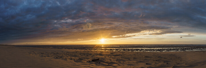 Panorama of sunset with dramatic moody cloudy sky above the ocean of North Sea, De Haan, Belgium.