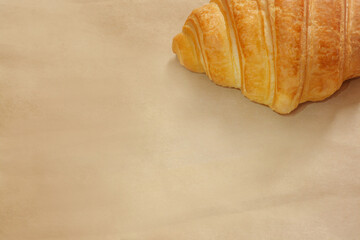 Beige kraft paper background with a croissant in the upper right corner, with copy space