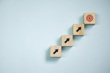 Top view wooden blocks set to step with icon arrow to target. Concept for growth business and...