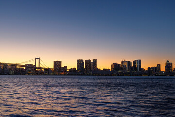 Fototapeta na wymiar 豊洲ふ頭から東京湾越しに見た芝浦ふ頭のオレンジ色に染まる夕焼けのビル群