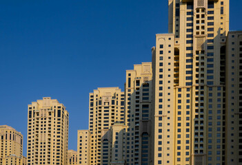 Fototapeta na wymiar Sand coloured towers of Jumeirah Beach Residence, blue sky background