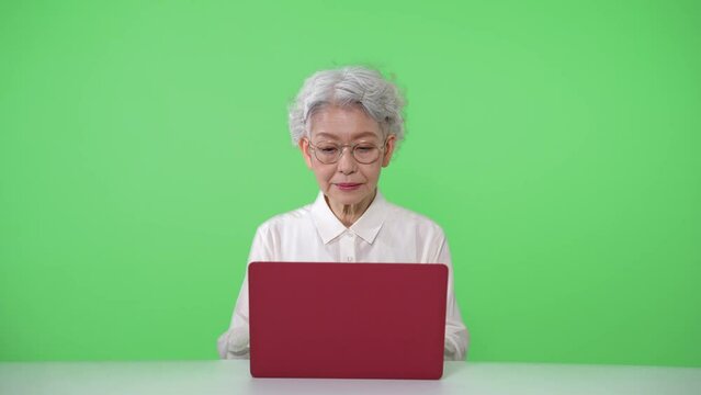 ノートパソコンを使うシニア女性　クロマキー合成用グリーンバック