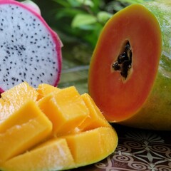 Cut papaya, dragonfruit and mango in the table close up.
