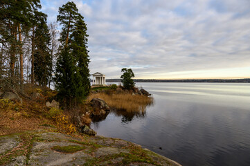 White antique pavilion building temple of Neptune in Mon Repos landscape by the lake.