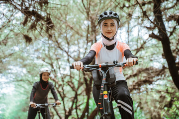 Young muslim woman wearing sportswear and cycling helmet with her friends outdoors