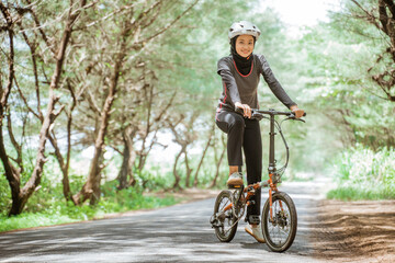 Asian woman in sportswear and helmet while cycling on outdoor background