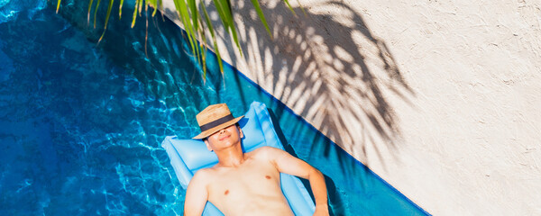Asian traveler man sleep on pool float air mat in the swimming pool in tropical resort hotel...