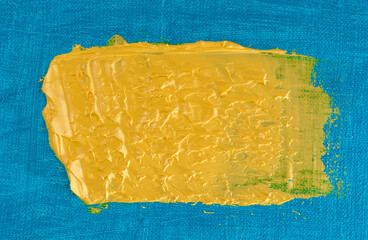 abstract bright color background: flat wide spot of yellow paint on blue fabric
